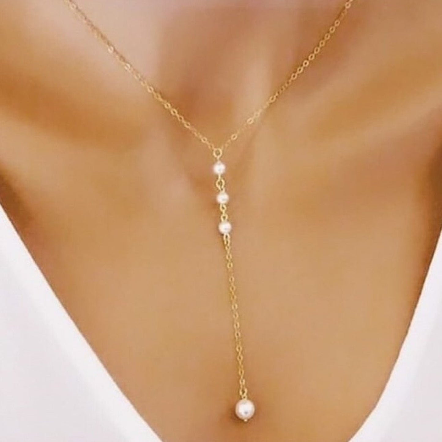 Gold necklace with pearl drops on a model wearing a white top