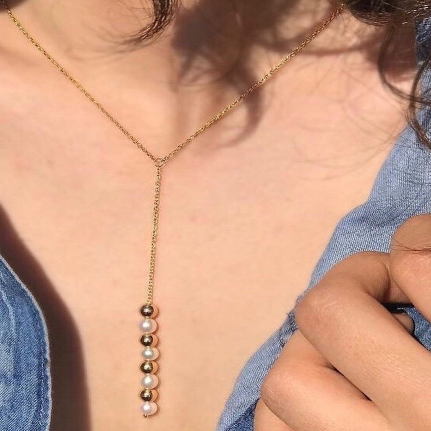 Necklace with colored beads worn by a person against a blue denim background