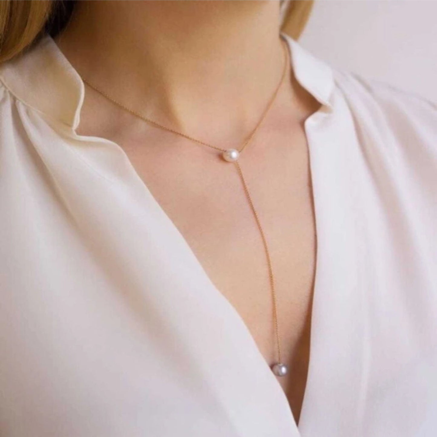 Pearl necklace worn by a person in a white blouse