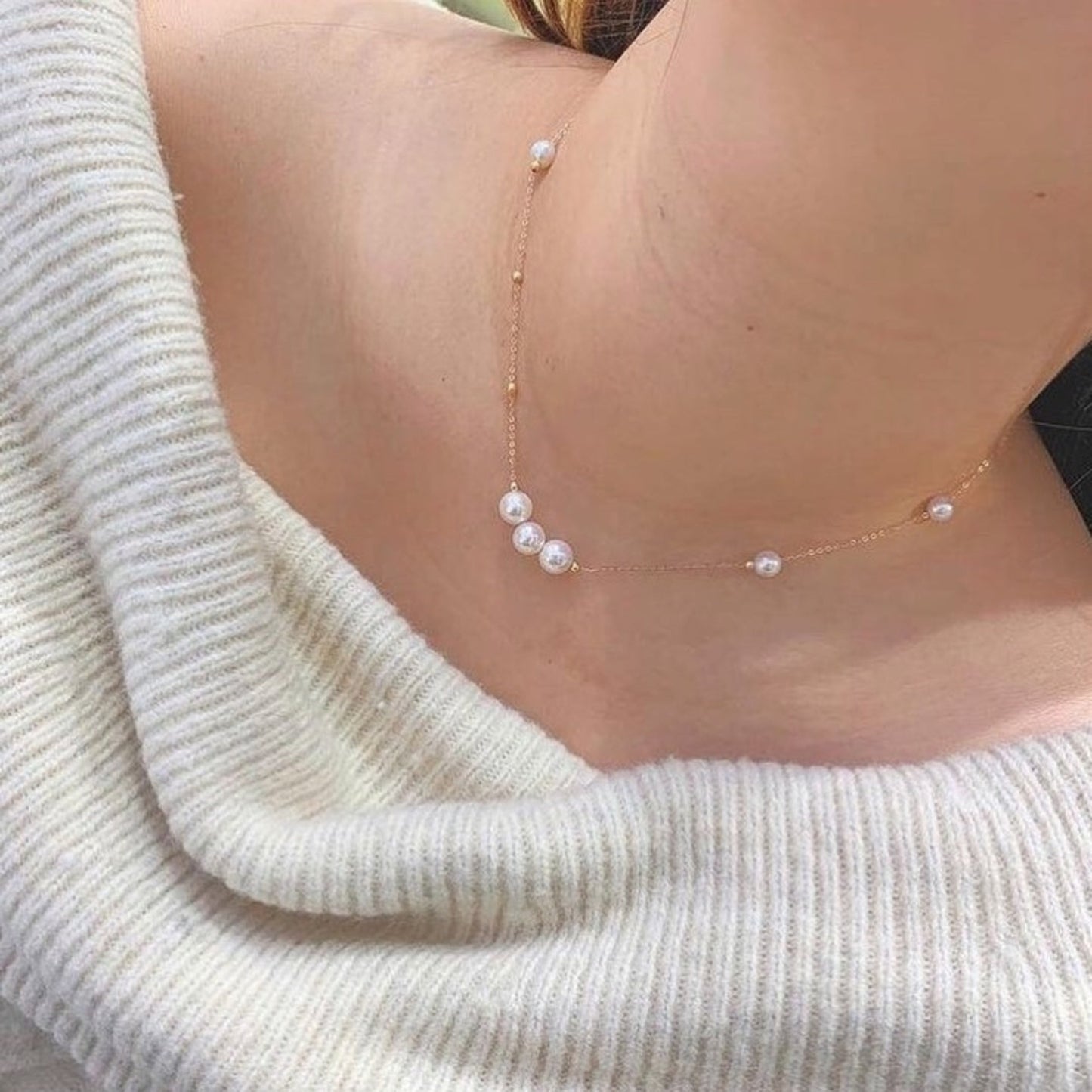 Pearl necklace worn by a person with a light-colored sweater
