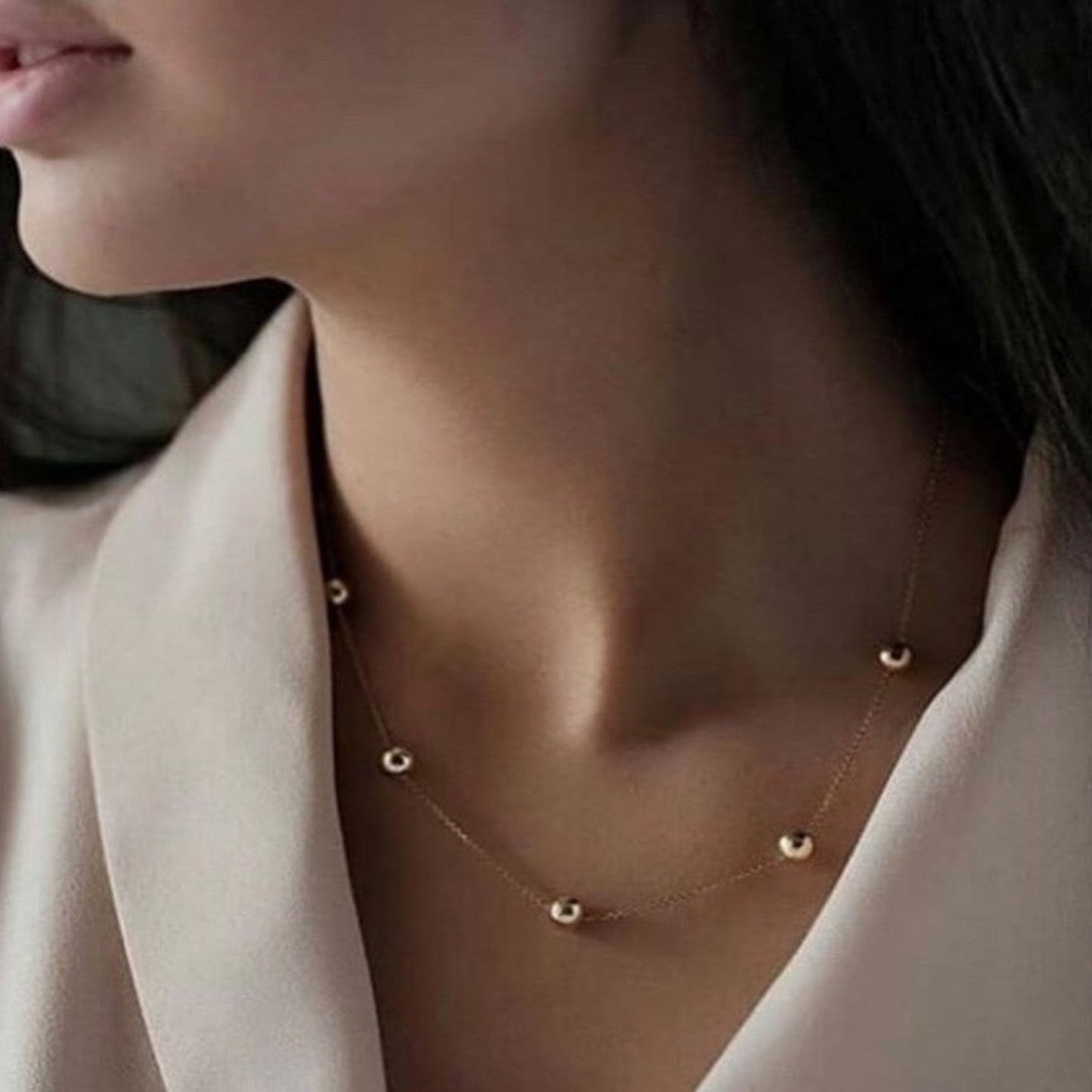Gold necklace on a person wearing a light-colored top