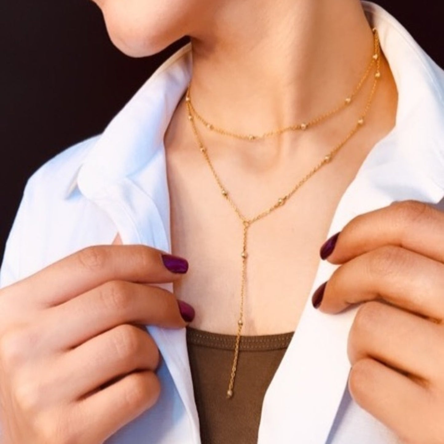 Person wearing a gold necklace with a plain background