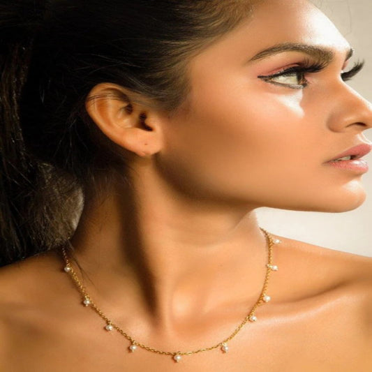 Close-up of a woman wearing a delicate necklace with a blurred background