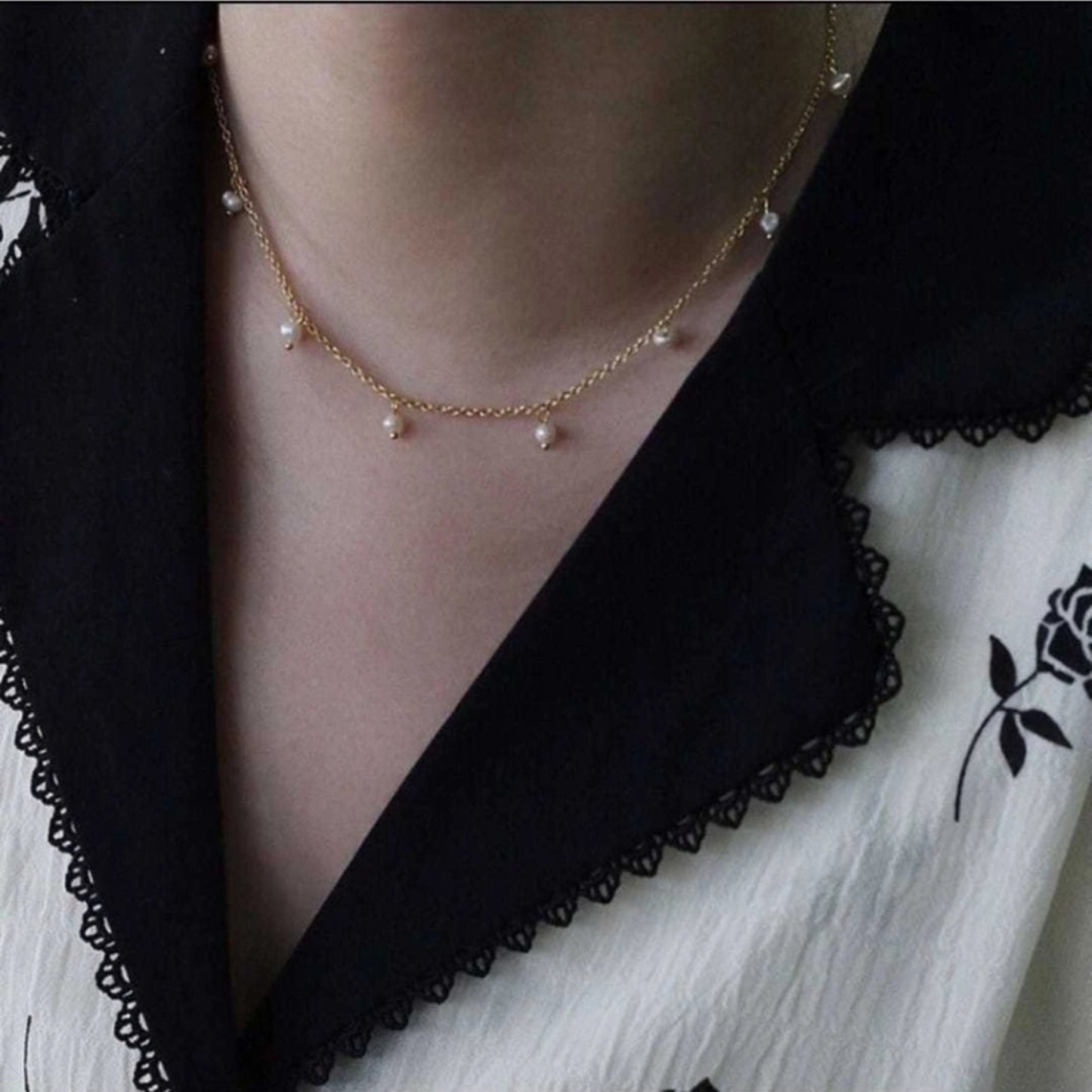 Pearl necklace worn by a person with a black and white outfit