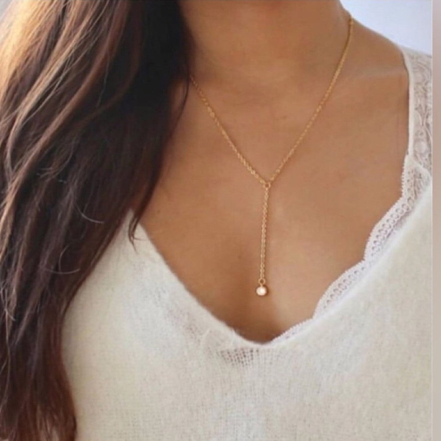 Gold necklace worn by a person with a white top