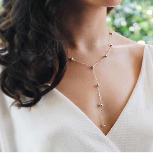 Woman wearing a delicate necklace with a blurred green background