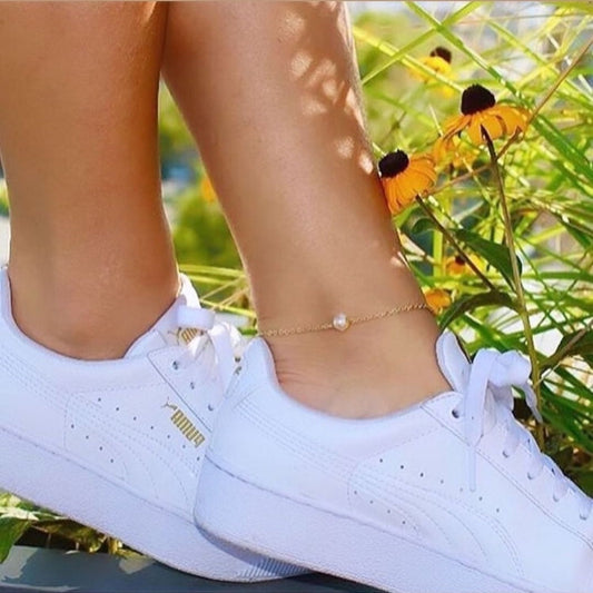 White sneakers worn with a background of greenery and flowers