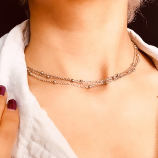 Close-up of a person wearing a delicate necklace with a blurred background