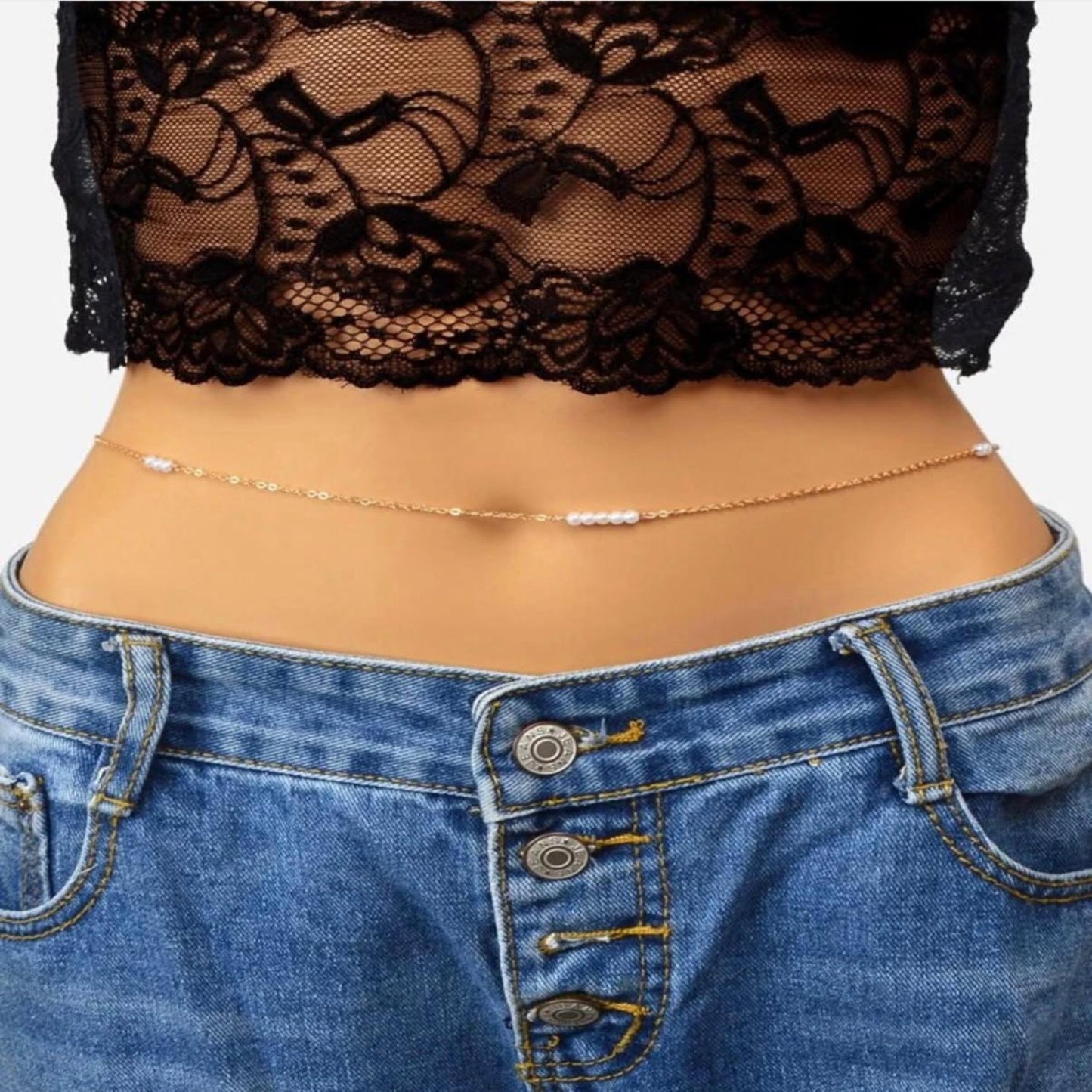 Close-up of a person wearing blue jeans with lace top and gold chain.