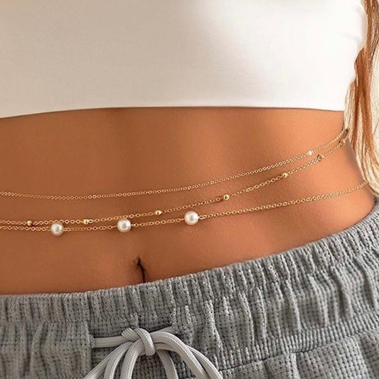 Gold chain belt with pearls worn by a person, focusing on the waist area.