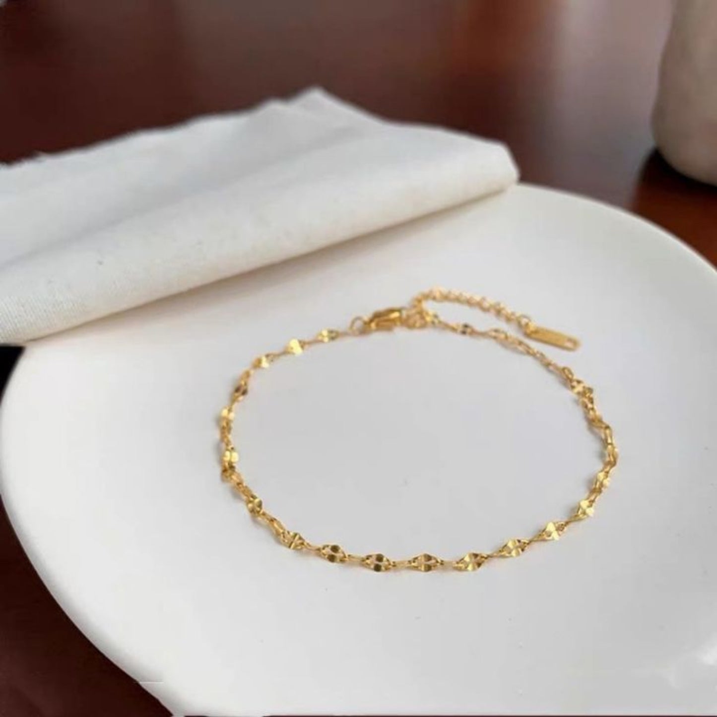 Gold bracelet on a white surface with a neutral background