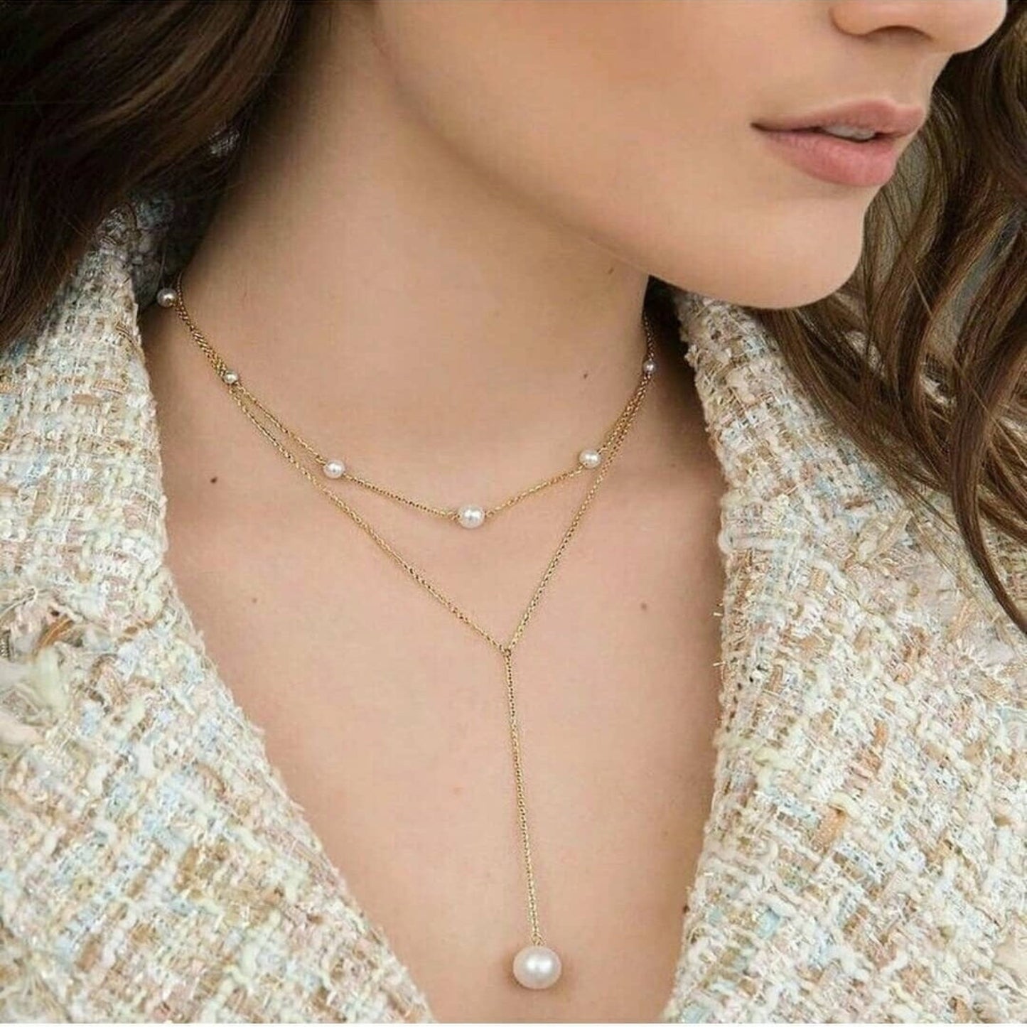 Woman wearing a delicate pearl necklace with a tweed jacket.