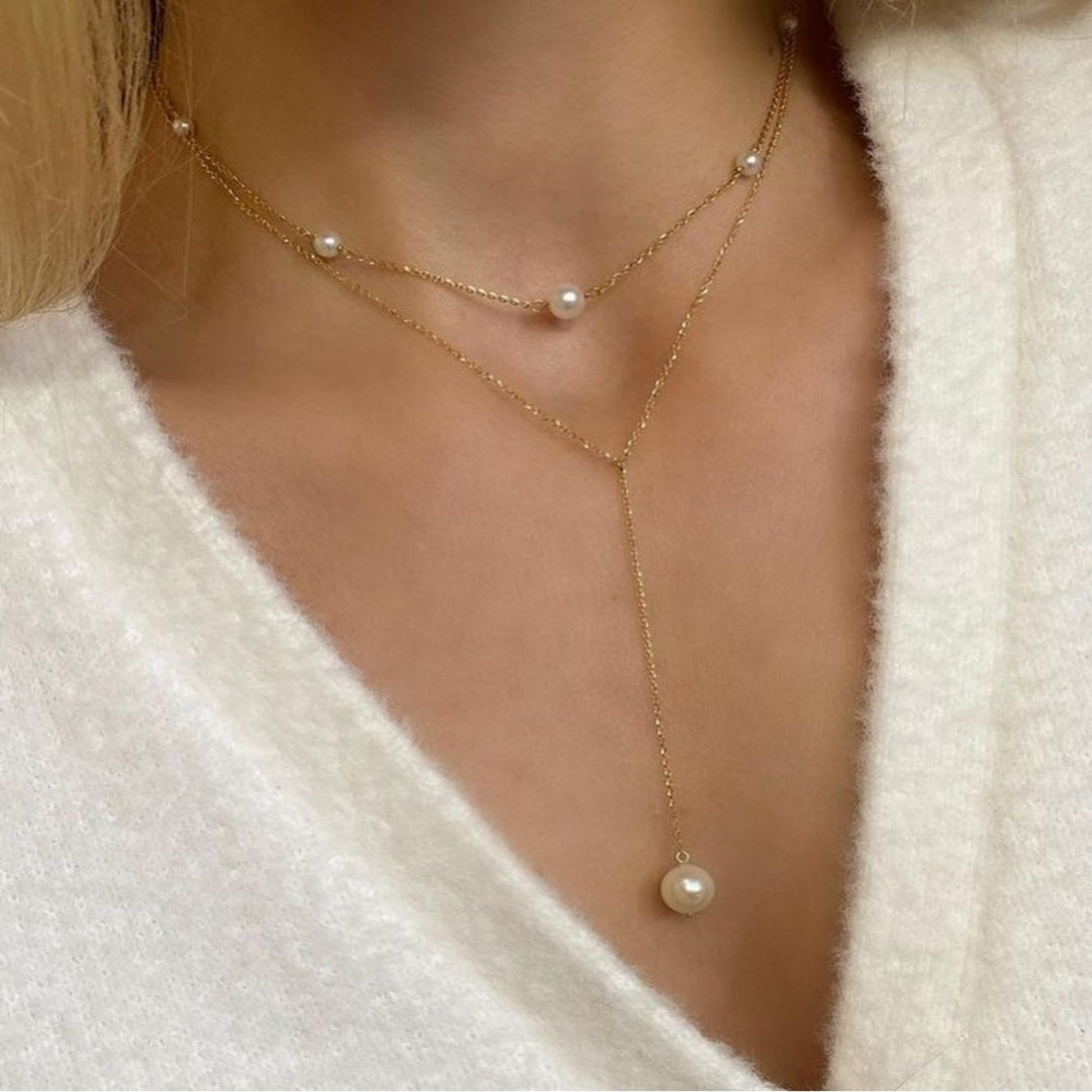 Layered gold necklaces with pearls on a person's neck.