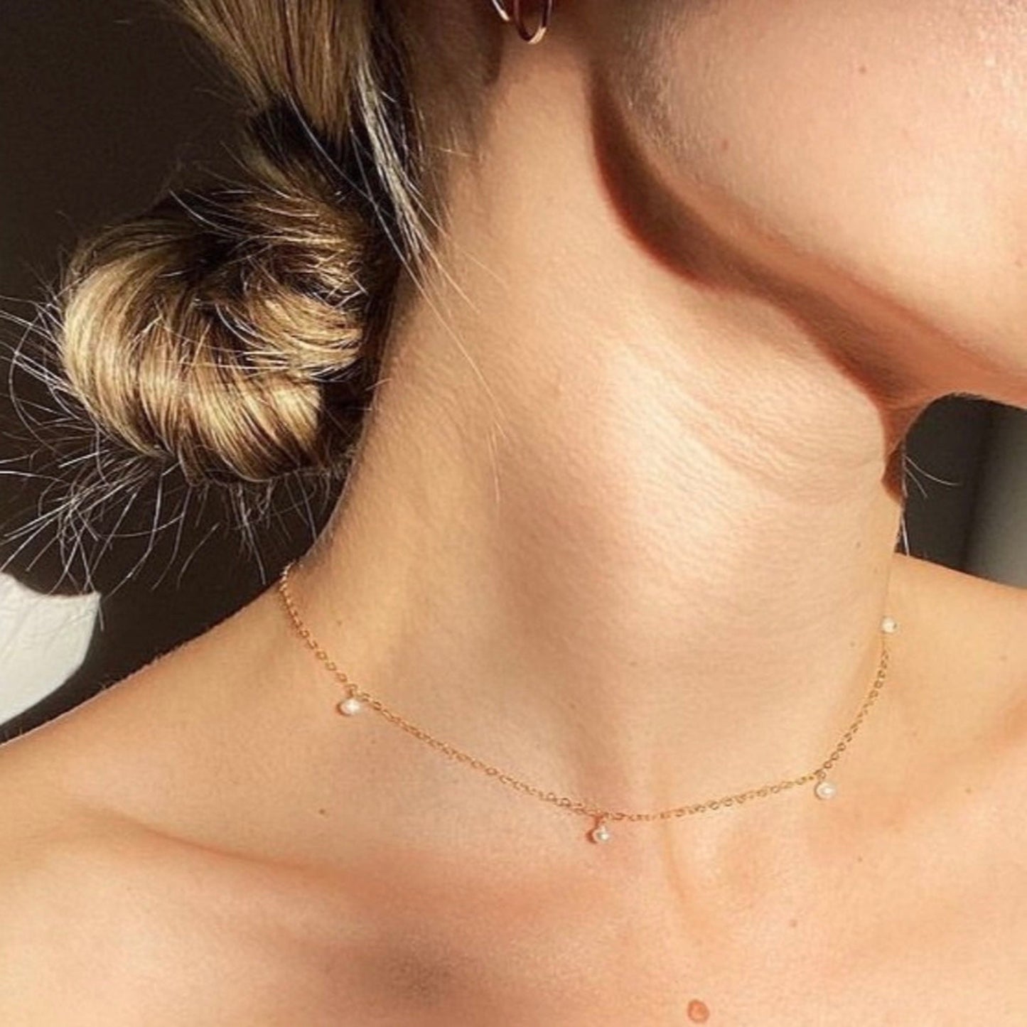 Close-up of a person wearing a delicate gold necklace with small beads.