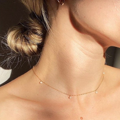 Close-up of a person wearing a delicate gold necklace with small beads.