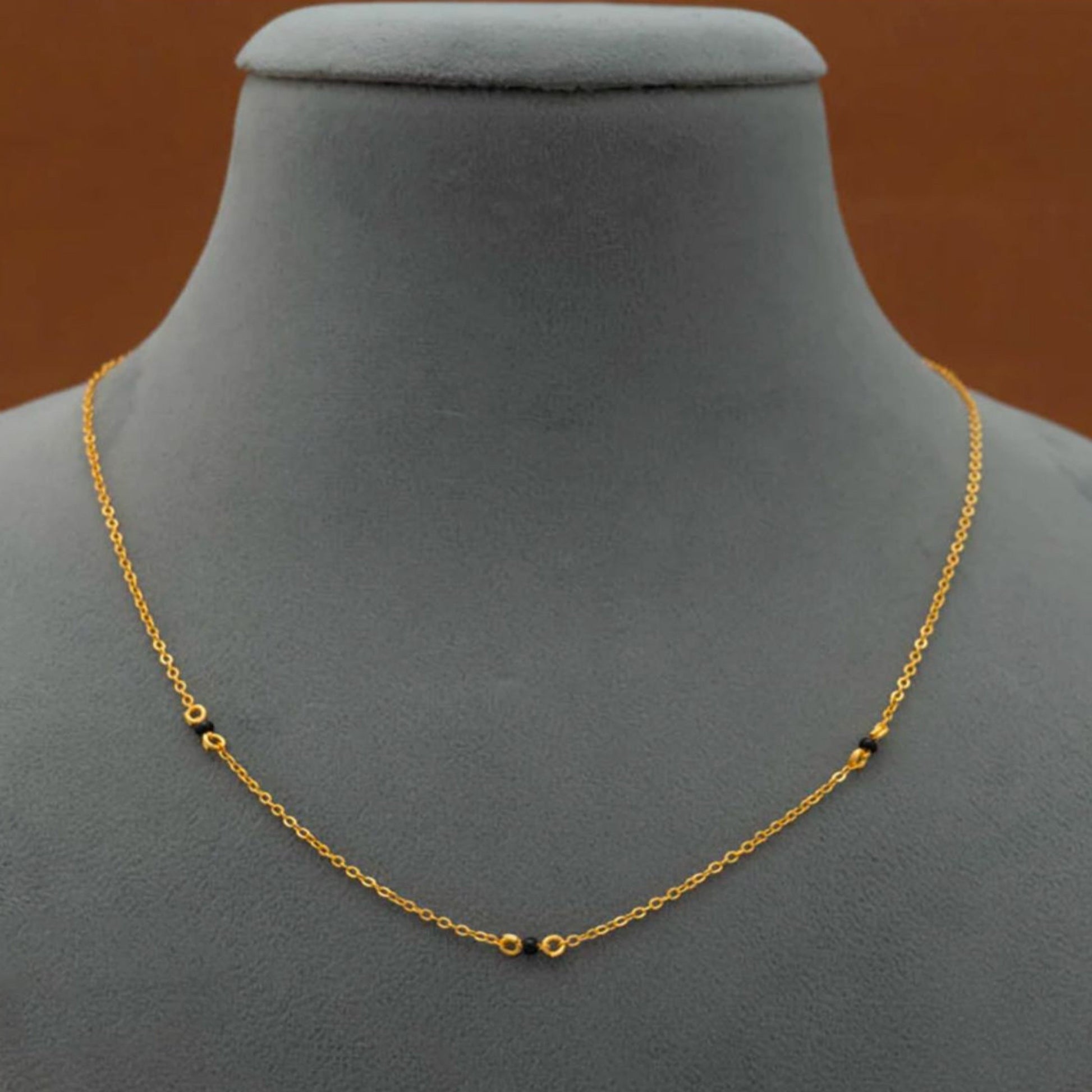 Gold chain necklace on a gray mannequin bust with a brown background