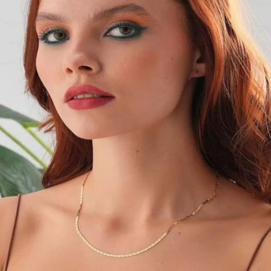 Woman wearing a gold necklace with a blurred background