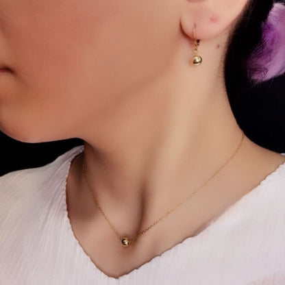 Close-up of a person wearing gold earrings and a necklace with a blurred background