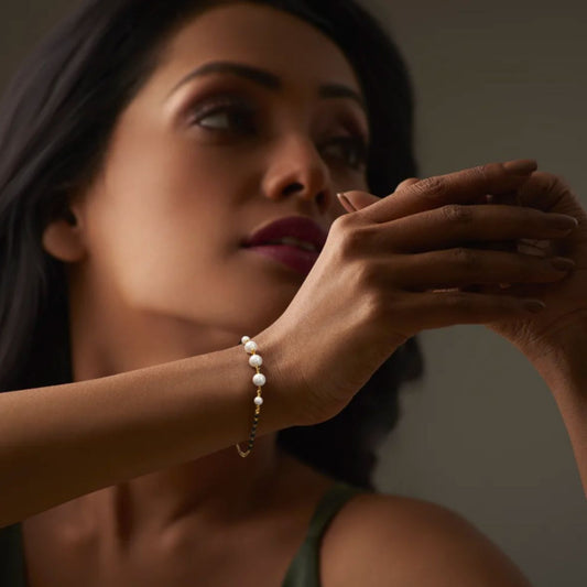Woman wearing a pearl bracelet against a neutral background