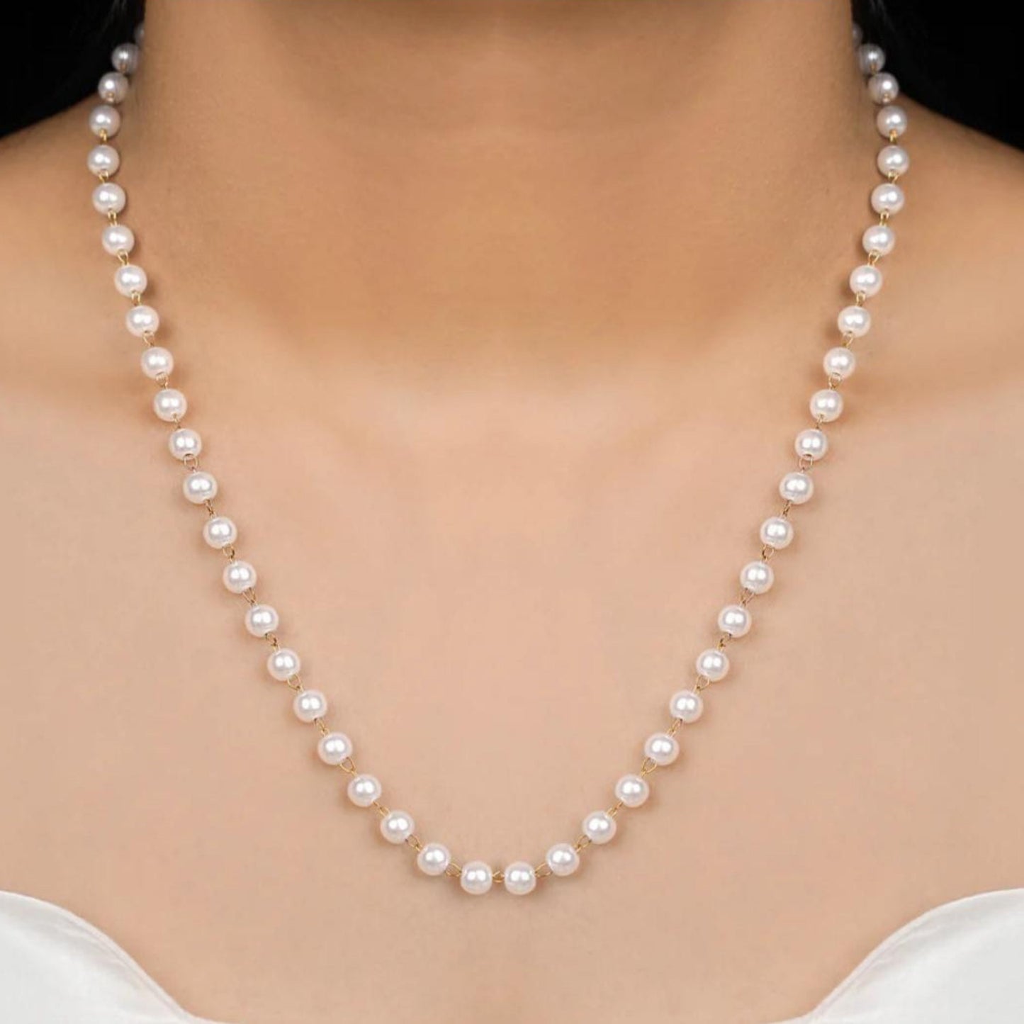 Pearl necklace being worn on a model with a plain background
