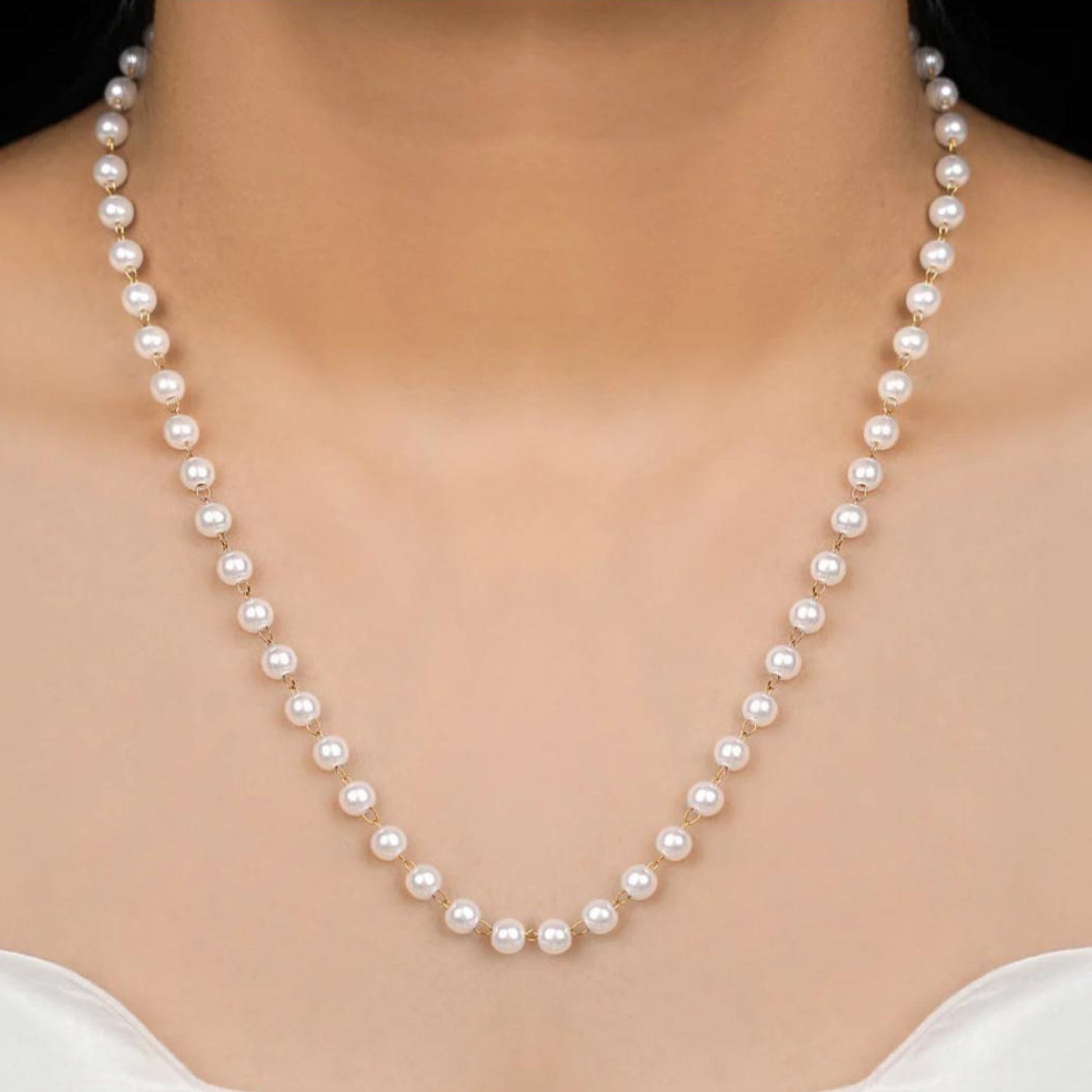Pearl necklace being worn on a model with a plain background