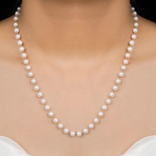 Pearl necklace being worn on a model with a plain background