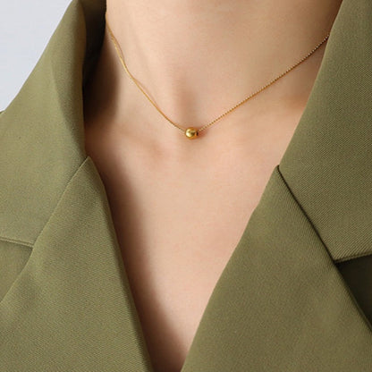 Gold necklace worn by a person with a green blazer
