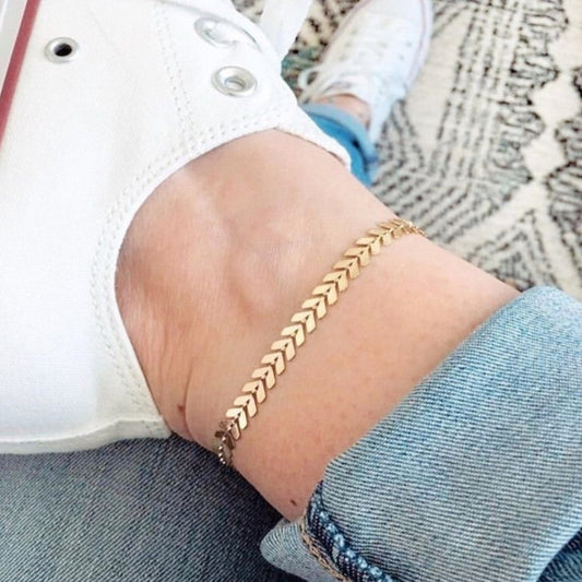 Gold chain bracelet on a wrist with a casual outfit