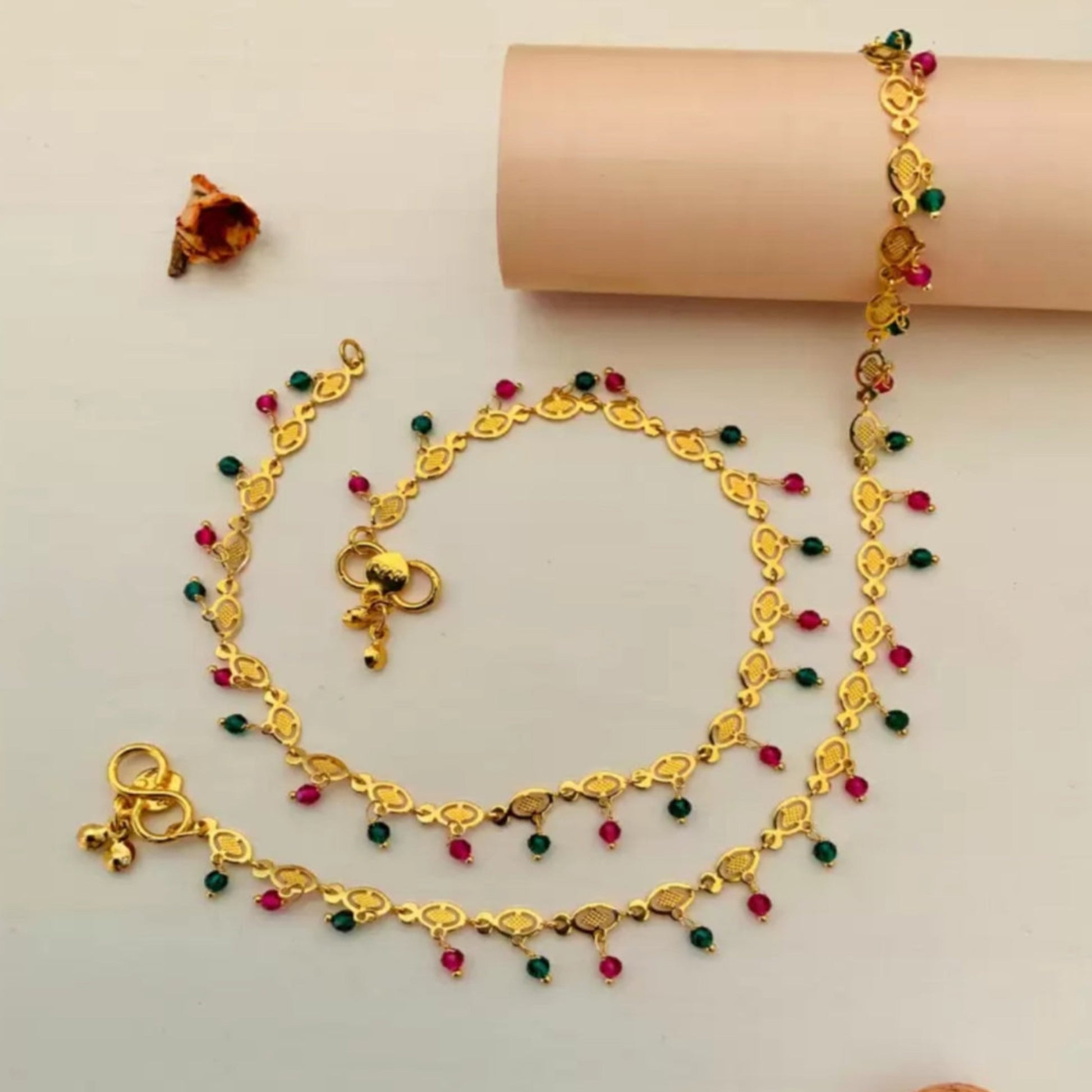 Gold necklace with colorful beads on a beige background