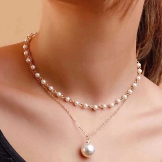 Pearl necklace with a pendant on a person against a beige background