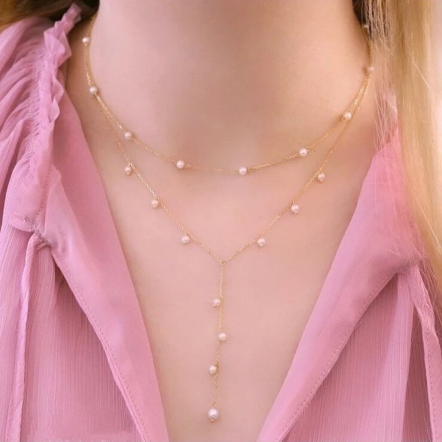 Pearl necklace worn by a person with a pink top