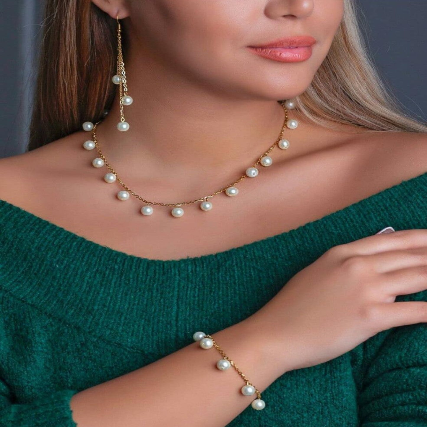 Woman wearing a pearl necklace and bracelet against a dark background