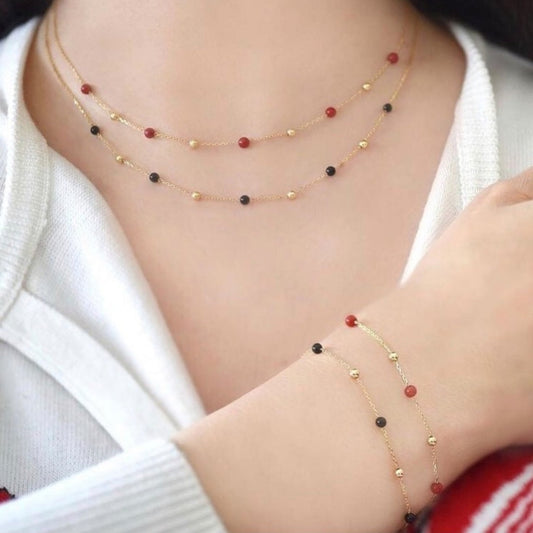 Necklace and bracelet set with red and black beads on a white background