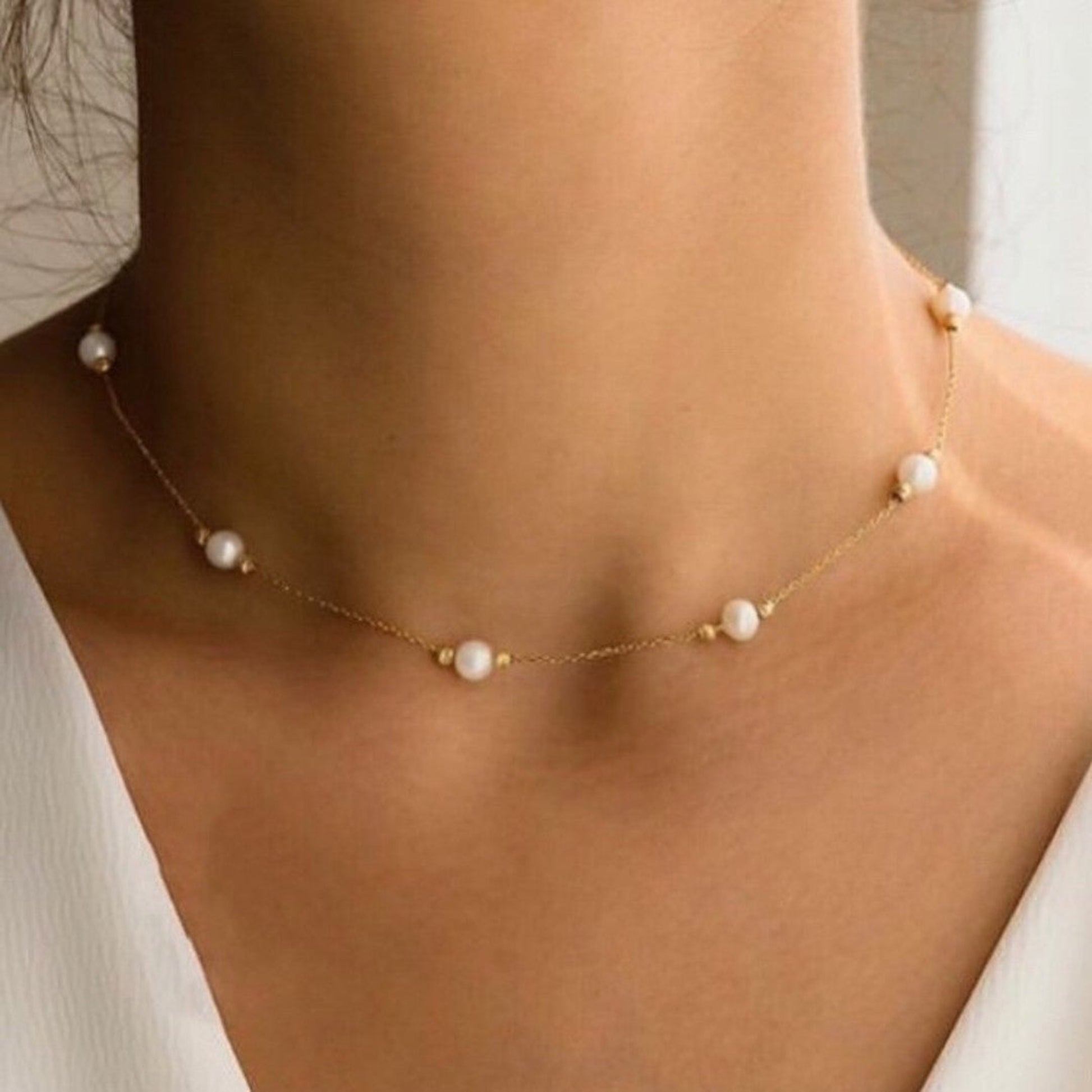 Pearl necklace on a person wearing a white top