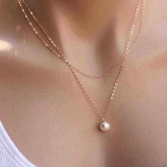 Gold necklace with a pearl pendant on a blurred background