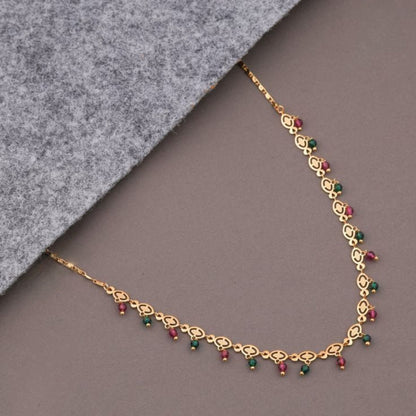 Gold necklace with colored beads on a gray surface