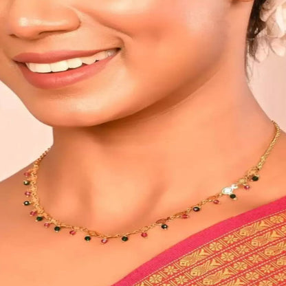 Woman wearing a gold necklace with gemstones on a pink and gold saree.