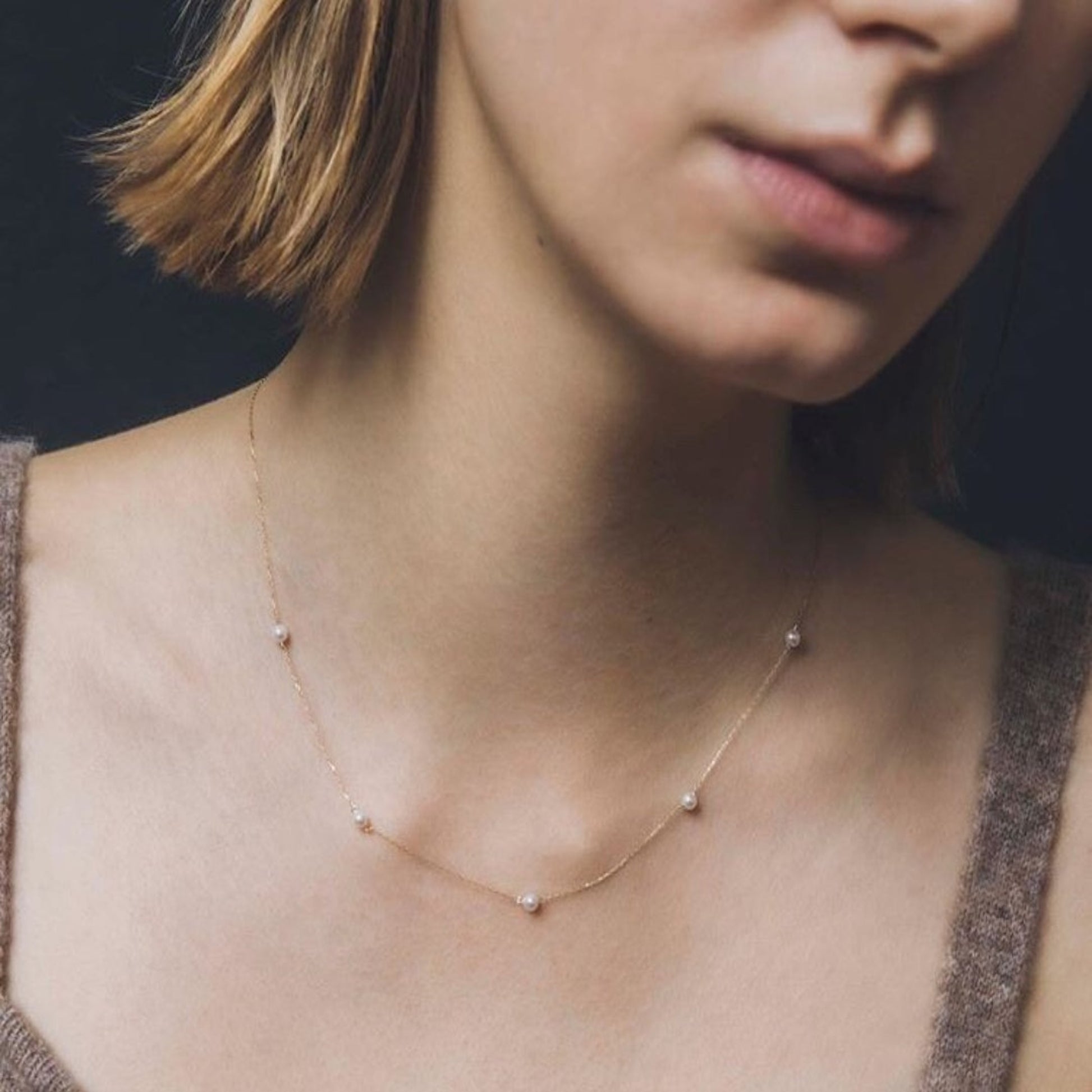 Close-up of a person wearing a delicate necklace with small beads.