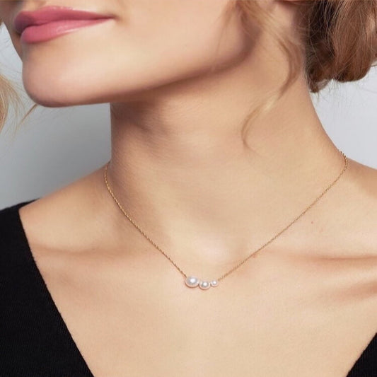 Pearl necklace worn by a person with a neutral background