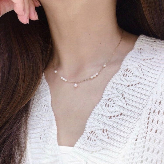 Pearl necklace worn by a person with a white textured top
