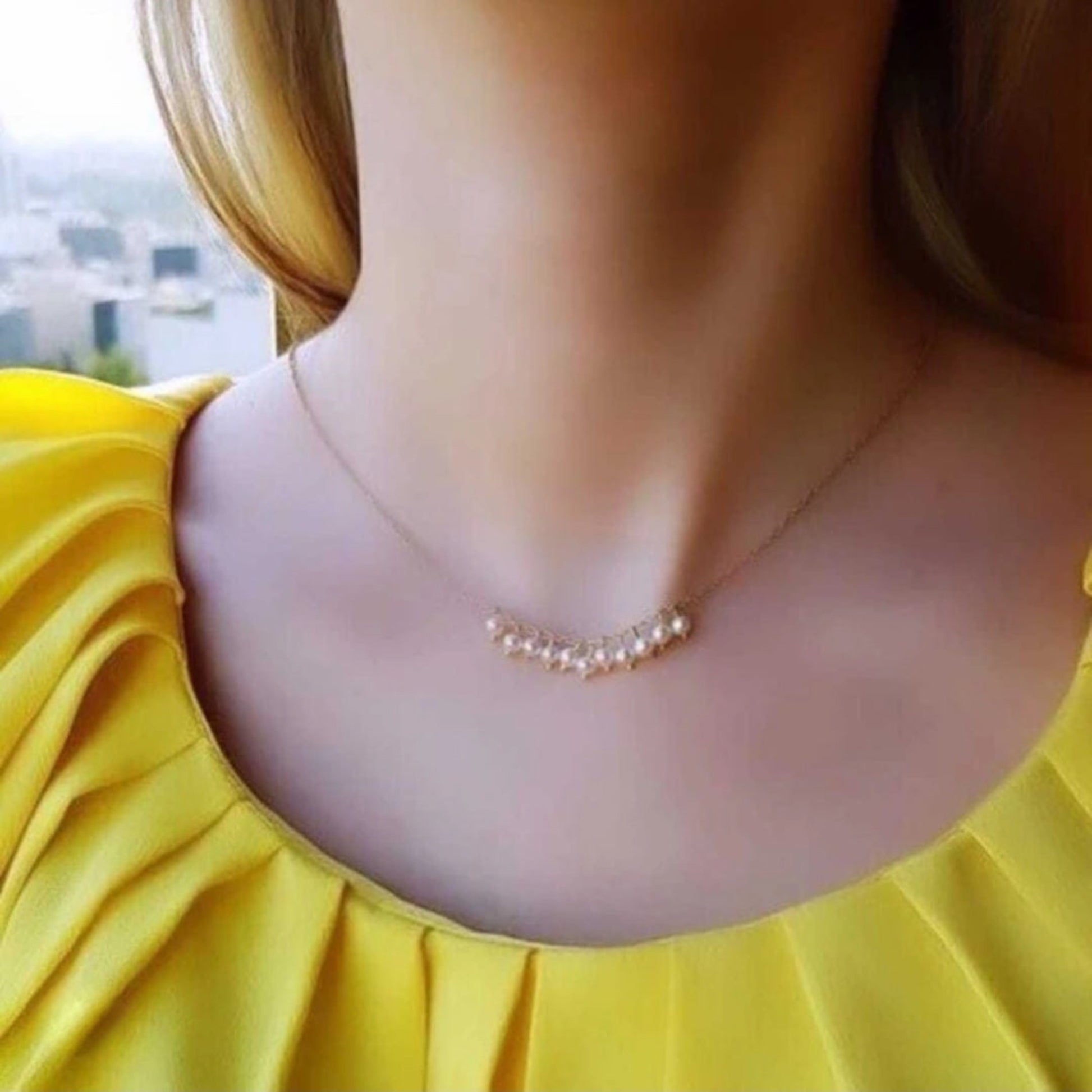 Necklace on a person wearing a yellow top with a blurred background