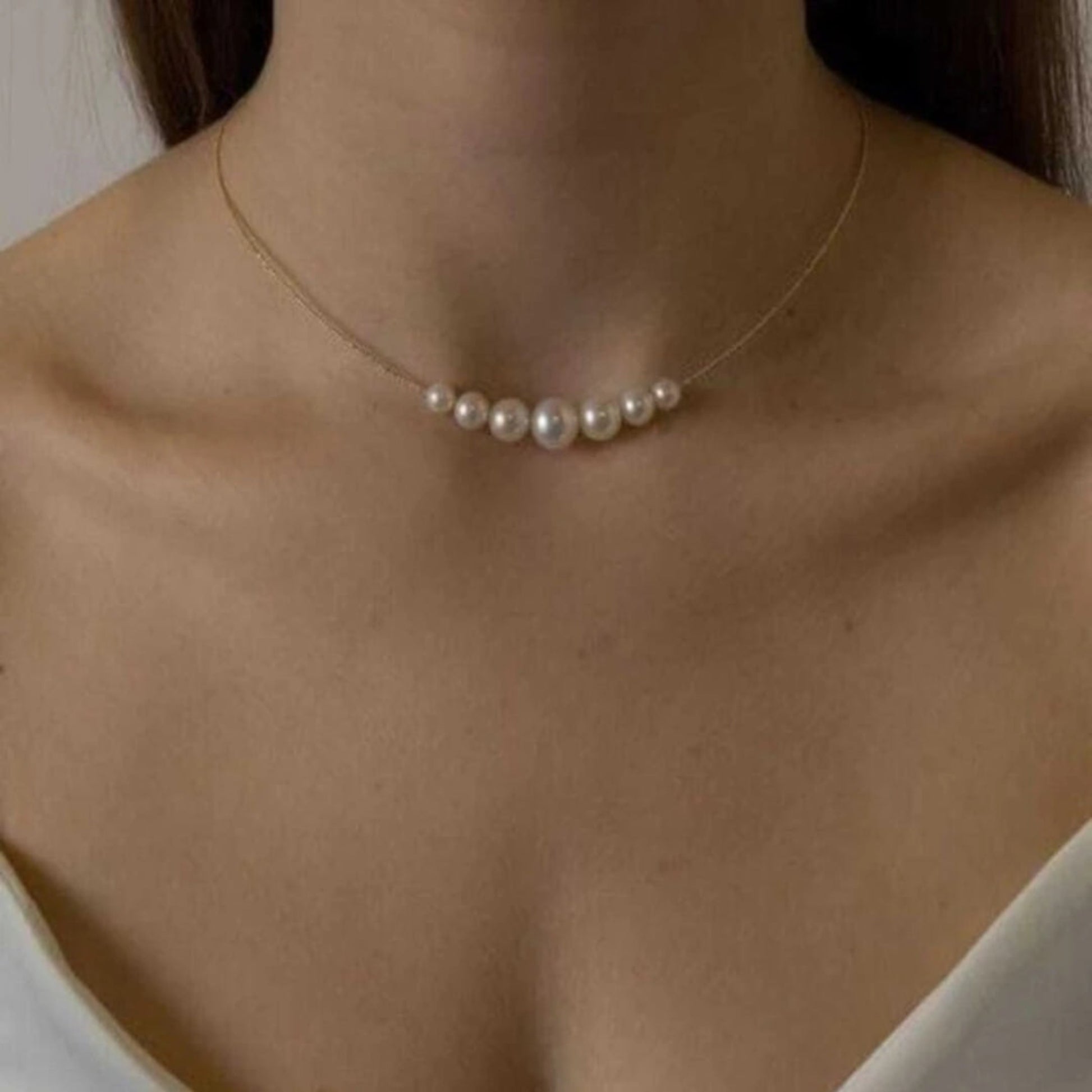 Pearl necklace on a person with a neutral background