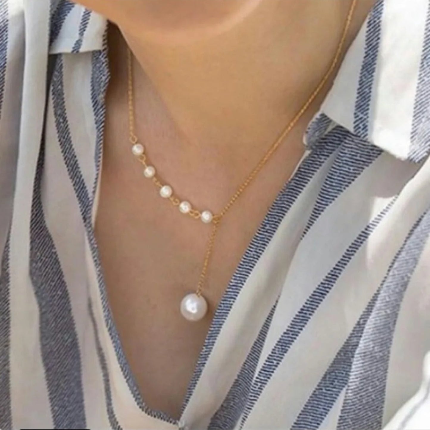 Pearl necklace worn by a person with a striped shirt