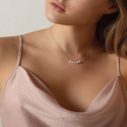 Close-up of a woman wearing a pearl necklace with a plain background