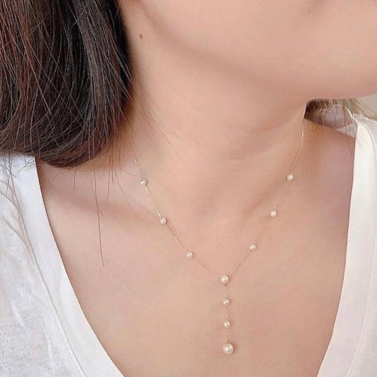 Pearl necklace worn by a person with a white top
