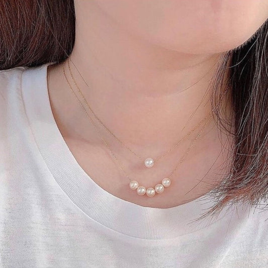 Pearl necklace worn by a person with a plain background