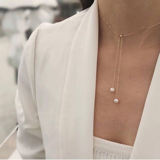 Pearl necklace worn by a person in a white outfit with a blurred background