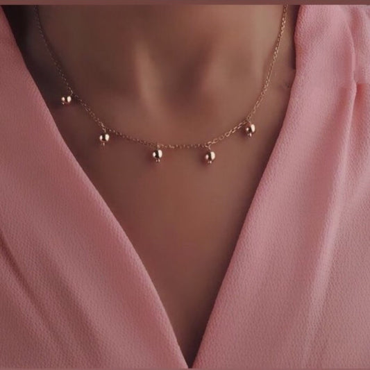Gold necklace with small beads on a pink garment