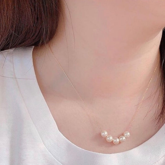 Pearl necklace worn by a person with a blurred background