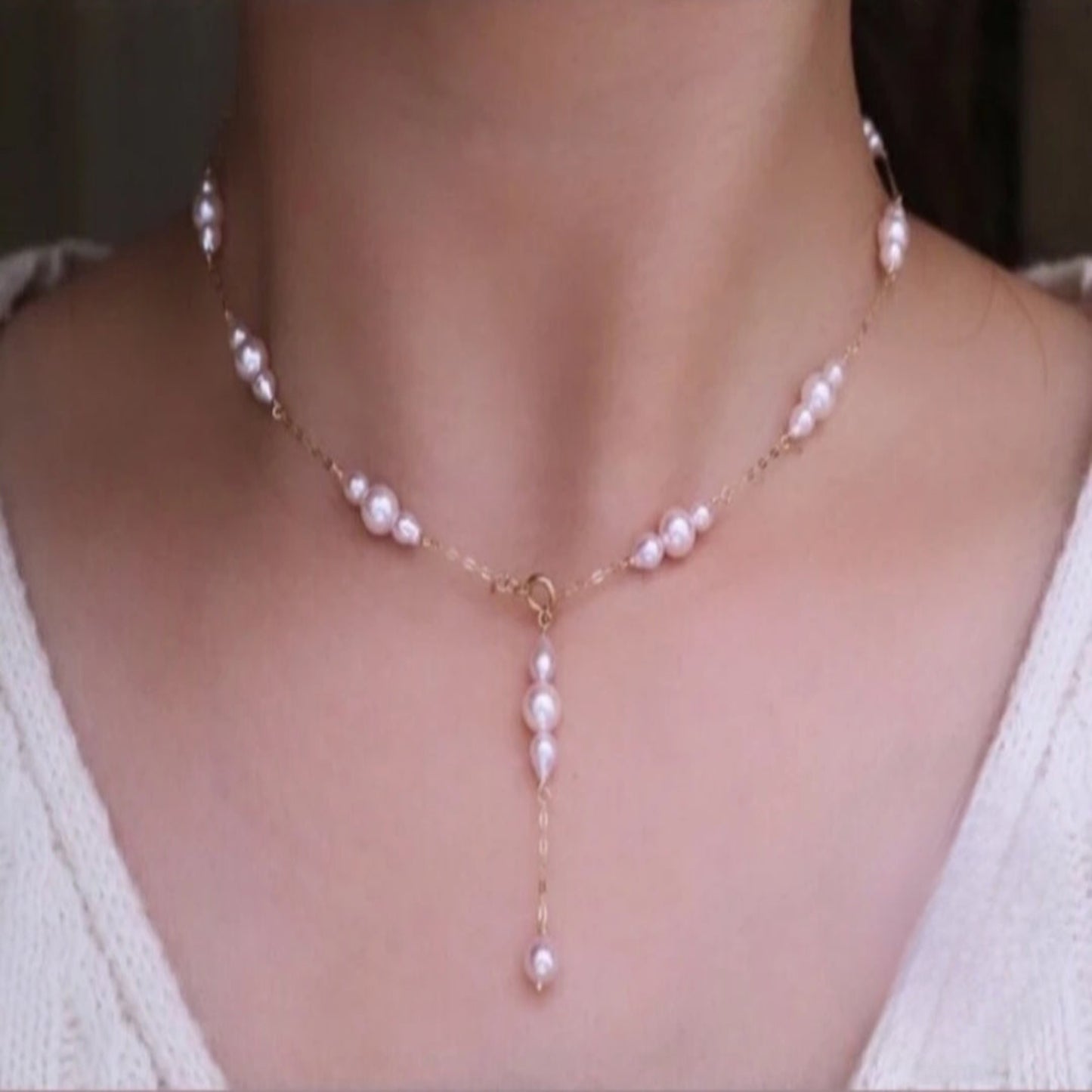 Pearl necklace on a person wearing a white top